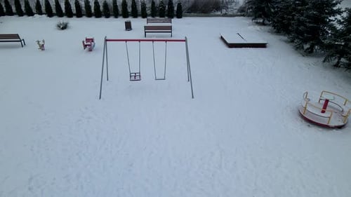 Empty Swing And Benches On Snow-covered Playground During Winter Season In Lubawa, Poland. aerial pu