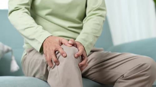 Homem idoso asiático sente dor no joelho.