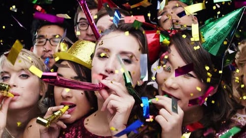 4k video footage of a group of people blowing party horns against a studio background