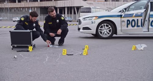 A polícia está investigando ativamente a cena marcada com marcadores de evidências e um carro patrulha