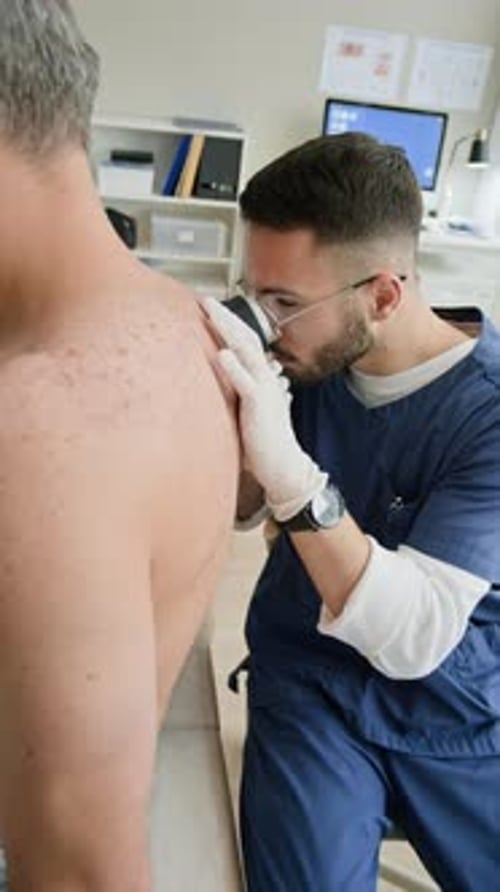Male Dermatologist Examining Skin Condition on Back of Patient