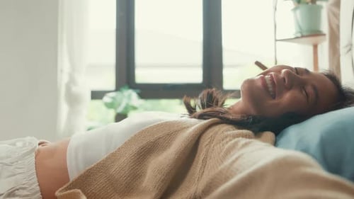 Close-up Asian girl with white cream pajamas lay head down on pillow close eyes happy smiling feel.