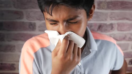 Adolescente enfermo con gripe, soplado en la nariz con servilleta