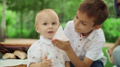 Portrait of Elder Brother Taking Care About Small Boy at Picnic. Cheerful