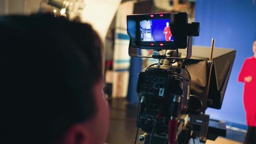 Cameraman Monitoring Presenter on Blue Screen Stage During Studio Recording Session