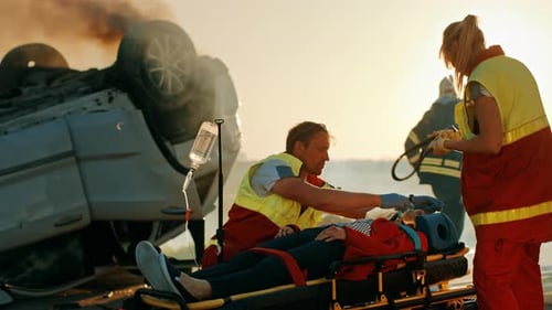 On the Car Crash Traffic Accident Scene: Paramedics Saving Life of a Female Victim who is Lying on