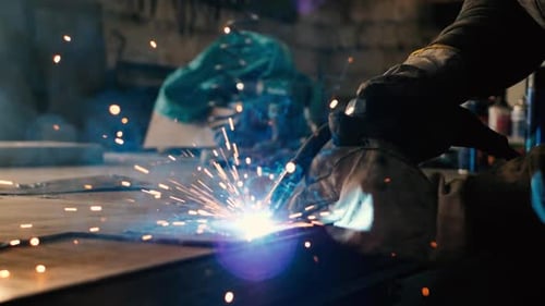 Welder on the table welds a set of metal parts. Welder working. Working with metal