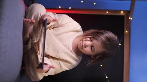 Vertical Girl Watches Cartoons on a Tablet Streaming Movies and Shows at Home