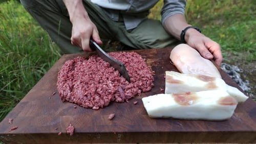 Homme coupant de la viande sur une planche à découper à l'extérieur