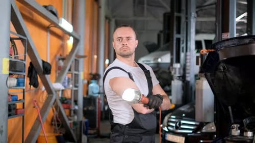 Un hombre está de pie en un garaje con los brazos cruzados