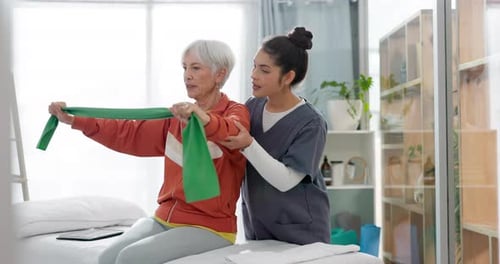 Senior woman doing a exercise with a resistance band for physiotherapy with a nurse in clinic