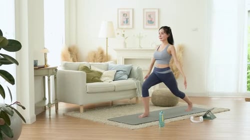 Asian woman in sportswear exercising and doing yoga in living room at home