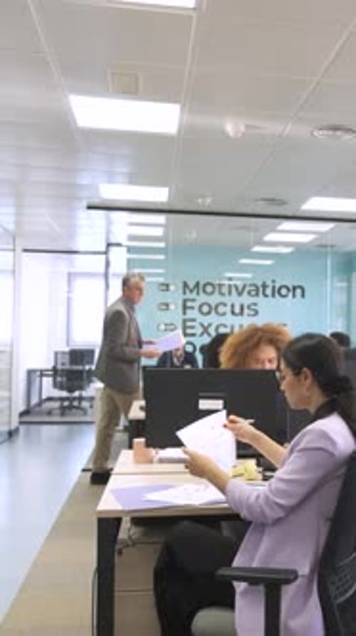 Manager Giving Files to Creative Professionals in Coworking Workspace