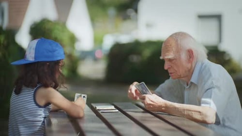 Grandfather and his grandson playing cards in the city park, dolly shot