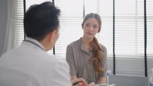 Una joven asiática visita y consulta un problema de salud con un médico en el hospital.