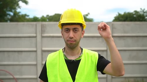 Industrial Worker In Reflectorized Vest Knocks On Yellow Hard Hat With Hand. medium shot, slow motio