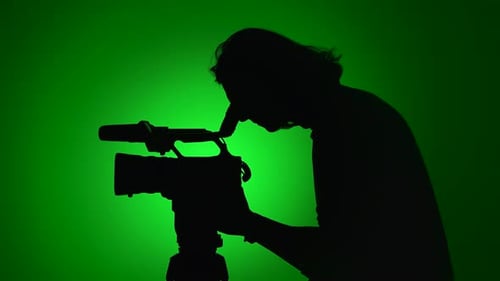 Silhouette of a Cameraperson Filming with Green Background