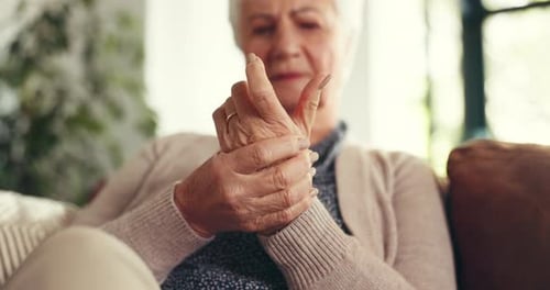Elderly woman, hands and pain with arthritis for joint inflammation or wrist injury on sofa in home
