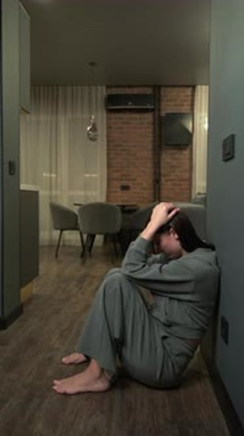A Sad Woman During Depression Sits on the Floor at Home and criesVertical Video