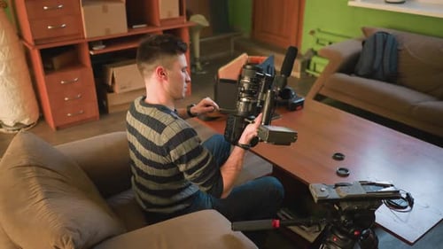 Studio Guy Adjusting Camera Lens on Tripod in Home Studio