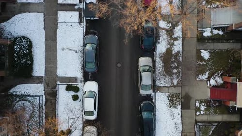 Aerial, rows of cars parked on residential street with winter snow, top down