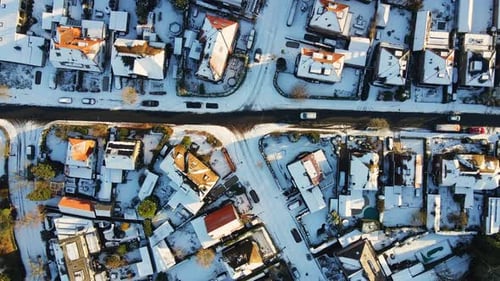 Top down aerial of a car driving slowly over a frozen route in a suburban neighborhood on a sunny wi