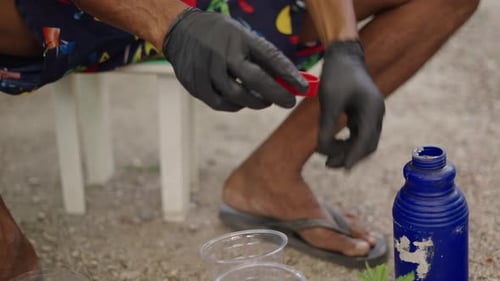 Foto de perto de mãos aplicando hormônios de crescimento em um clone de maconha