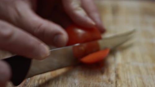 Slicing Red Cherry Tomatoes with Kitchen Knife on Wooden Board Preparing Heart Shaped Pizza for