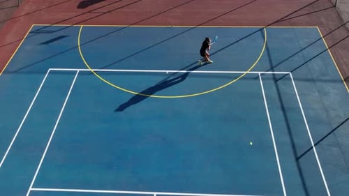 High angle long shadows, woman has tennis volley with unseen opponent