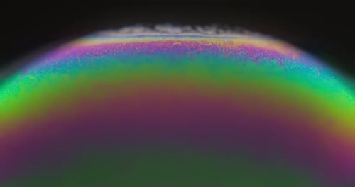 Macro Of Soap Bubble With An Iridescent Surface In Black Background.