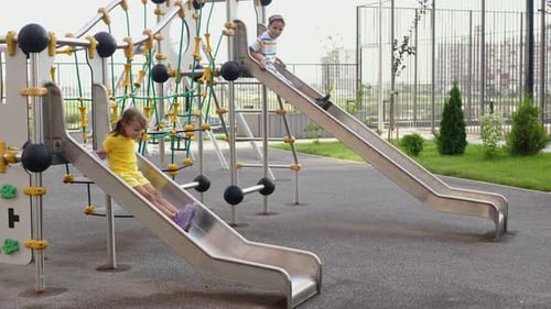 Children a Boy and a Girl Play on a Modern Playground Ride Slides