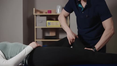 A Male Osteopath Performs Physical Therapy on a Female Patient The Doctor Looks at the Condition of