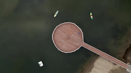 Aerial View of Stunning Circular Pier Surrounded By Boats Floating in Calm Serene Water Clip