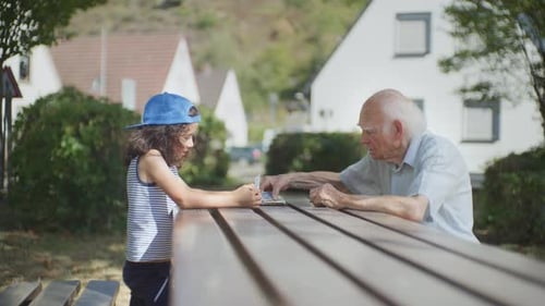 Grandfather taught his grandson how to play cards in the city park, half total shot