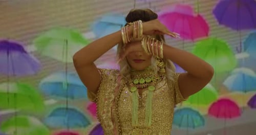 East Indian girl holding bangles to her face in a traditional indian wear outfit