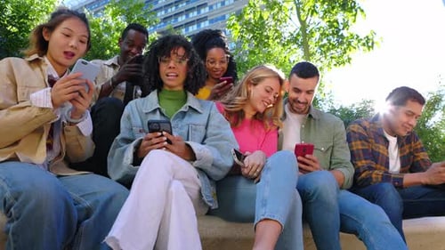 Young Group of Happy People Smiling While Using Mobile Phone Together Outdoors