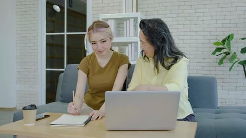 Mom and daughter shopping through e-commerce website on laptop and taking note in notebook