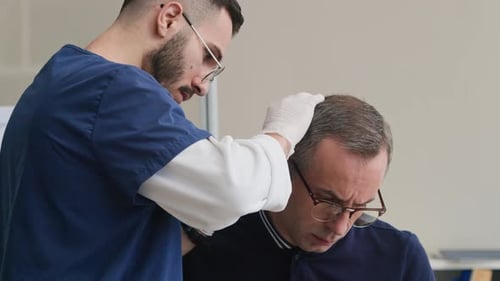 Young Dermatologist Examining Moles on Middle-Aged Patients Head in Clinic