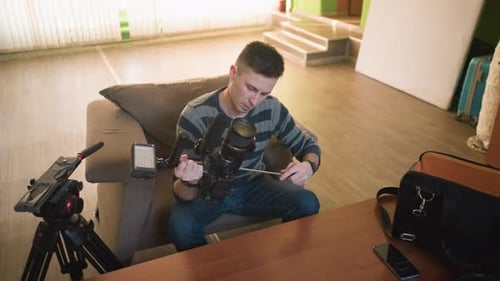 Studio Guy Adjusting Camera Lens Focused on Preparing Gear