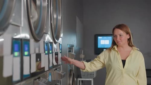 Business Woman Gliding Hand Across Industrial Washer in Modern Laundromat