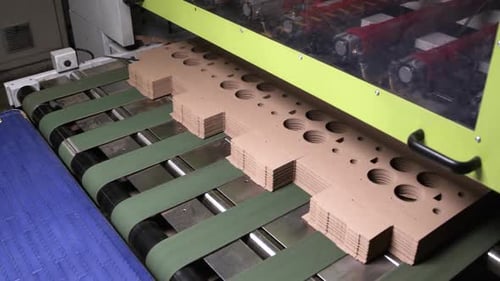 Aufgefaltete Getränkeboxen zum Mitnehmen, die mit einem Förderband transportiert werden