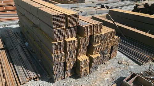 Aerial view of galvanized iron pipes stack and steel rectangular bars of metal