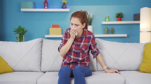 Mujer joven que se cubre la boca y la nariz mientras tose.