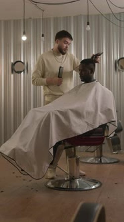 Barber Trimming Clients Hair with Clippers in Hairdressing Salon