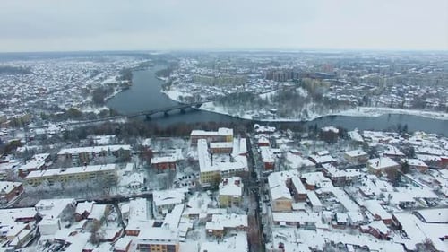 City panorama with river and bridge over it. Snowy winter daytime drone footage.