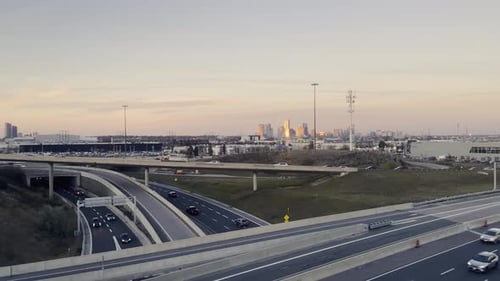 Toronto highway with car traffic and city skyline in background at sunset, Canada. Aerial view