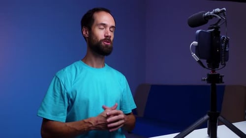 A Young Blogger Records a Video with Himself on His Phone in His Studio