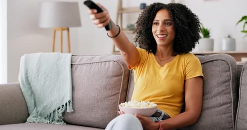 Black woman, remote control and popcorn in home living room with smile, funny movie