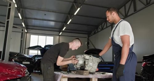 Mechanics Repairing Electric Car Engine in Workshop