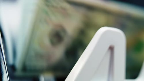 Close Up of Money Counting Machine Counting Hundred Dollar Banknotes